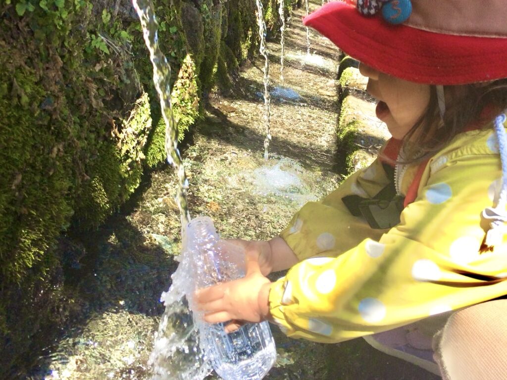 浅間大社で湧き水をペットボトルにくむ子どもの写真